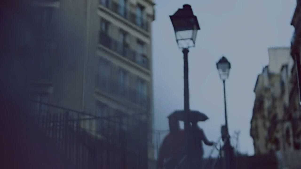 People walking a rainy Parisian street with soft blue lighting